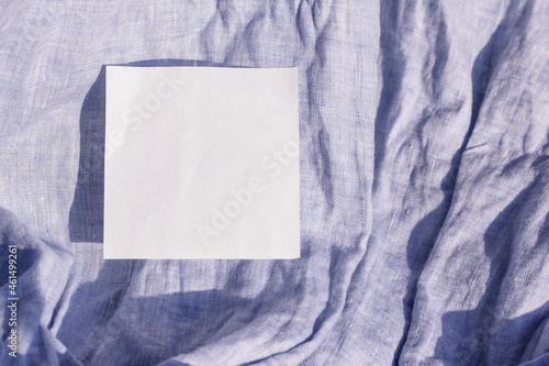 White square sticker on blue linen fabric. The price tag of the material.
