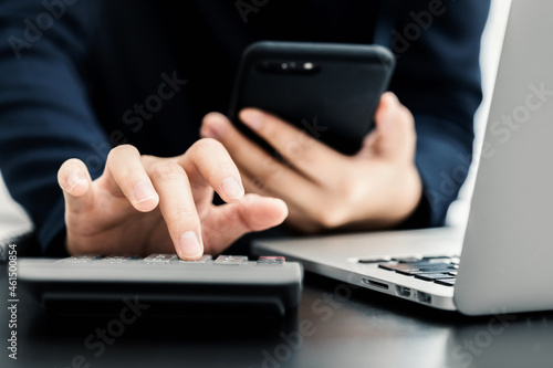 Close up of businesswomen working online via mobile smartphone and laptop computer for analytic business report on the workplace, freelance work from home, Planning financial and business concept.