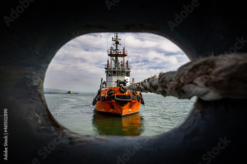 Tug boat pulling ship with rope. photo