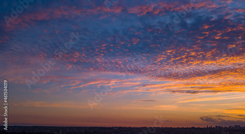 End of the day with a sky between clouds and very colorful, highlighting blue and orange. At the base of the image, and in the background, is the silhouette of the city. 