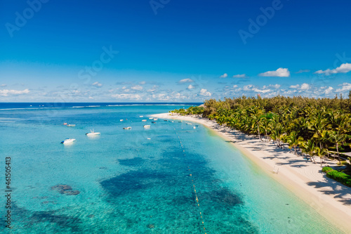 Tropical beach with mountain in Mauritius. Beach with palms and blue ocean. Aerial view