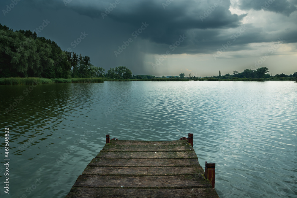 Wooden pier towards the lake and a thundercloud