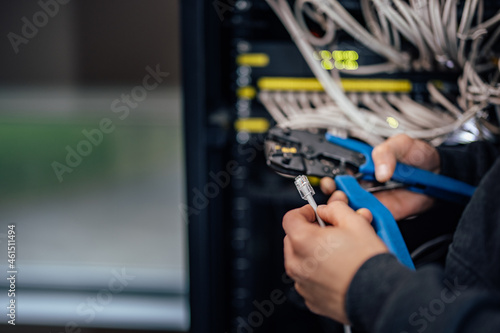 Technician holding hand crimping tool and ethernet cable. © bnenin