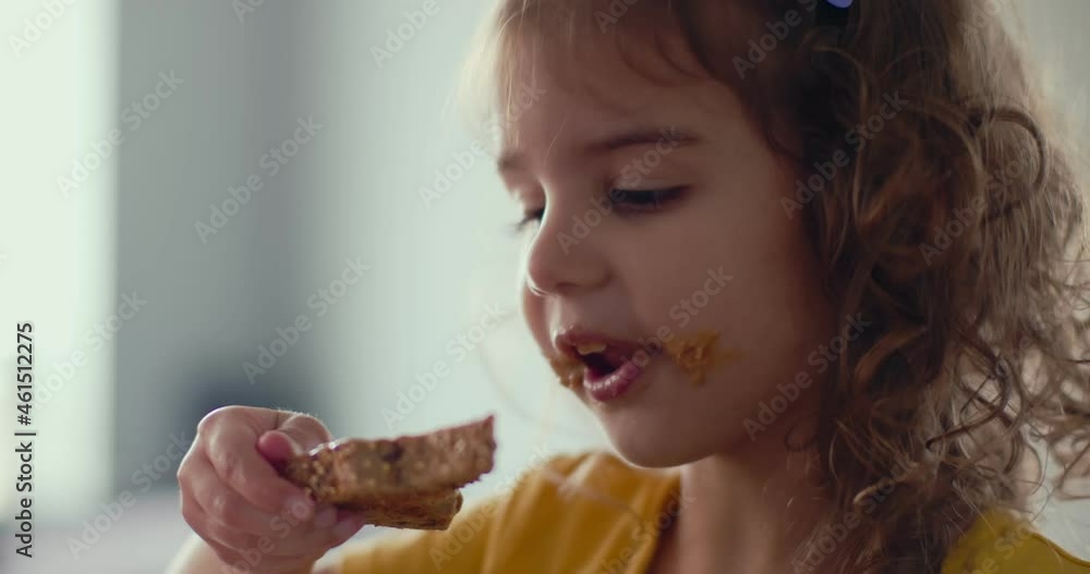Toddler girl eating a peanut butter sandwich snack at home. Toddler girl eating a peanut butter sandwich snack at home.