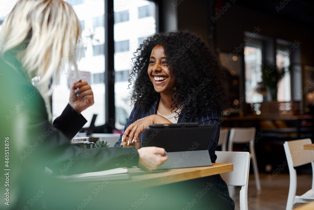 Female coworkers talking in cafe Female coworkers talking in cafe