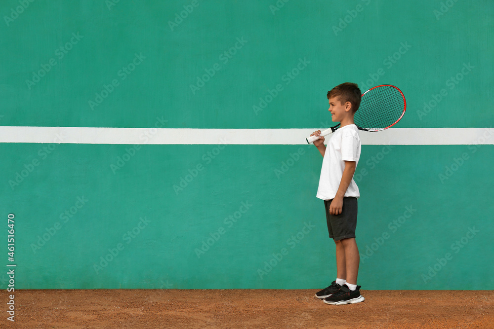 Cute little boy near green wall on tennis court. Space for text Cute little boy near green wall on tennis court. Space for text