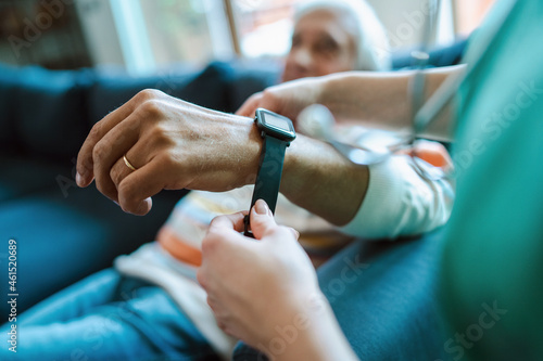 Smartwatch for assisted living. A woman from the medical health system wears a smartwatch for remote monitoring of vital signs on an elderly person photo