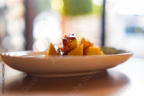 Plate of chopped mango with Mexican chamoy sauce and blurry background photo