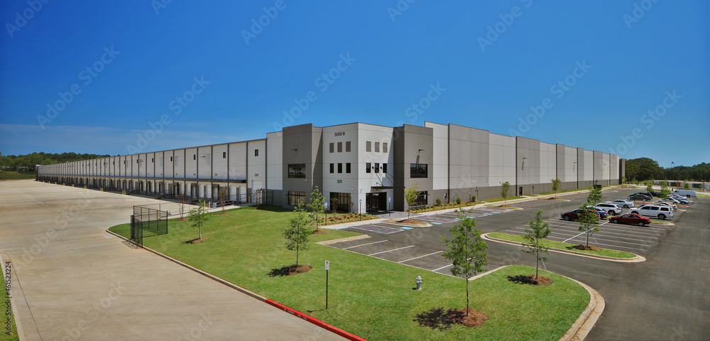 Modern gray industrial distribution warehouse and parking lot