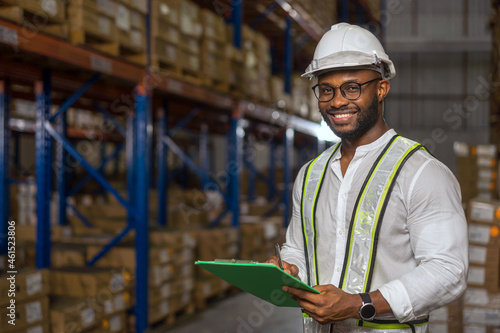Portrait of smiling warehouse officer checking stock and looking at camera. 