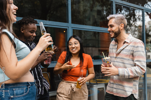 Happy diverse friends drinking cocktails at open air bar - Multiracial people, party and fun concept - Focus on african man face