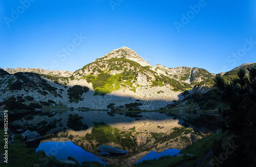 Reflection of rocky Muratov peak in the calm water of Muratovo lakes in Pirin mountain National park in Bulgaria