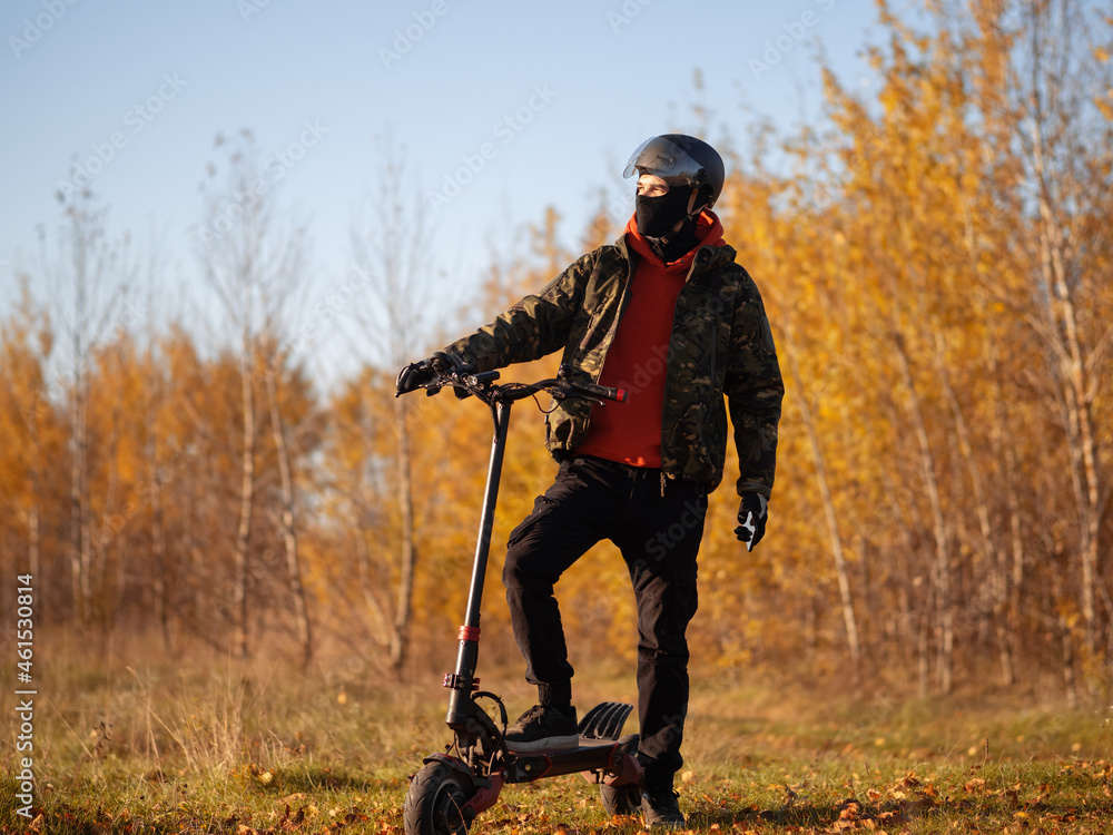 A man rides a powerful electric scooter on forest autumn roads A man rides a powerful electric scooter on forest autumn roads