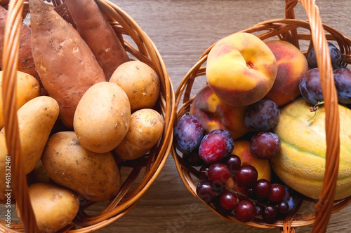 Two vintage baskets filled with various fruti and vegetable on wooden table. Top view. photo