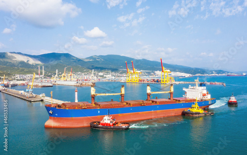 Industrial seaport Novorossiysk , top view. Bulk carrier, Multipurpose or General cargo enters the port using tugs.