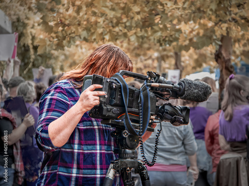 Obraz na płótnie Female television videographer with professional camera  filming at crowded prot