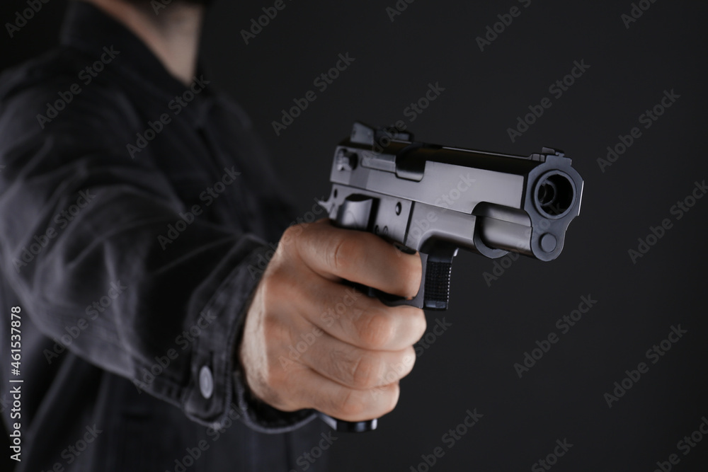 Man holding gun on black background, closeup Man holding gun on black background, closeup