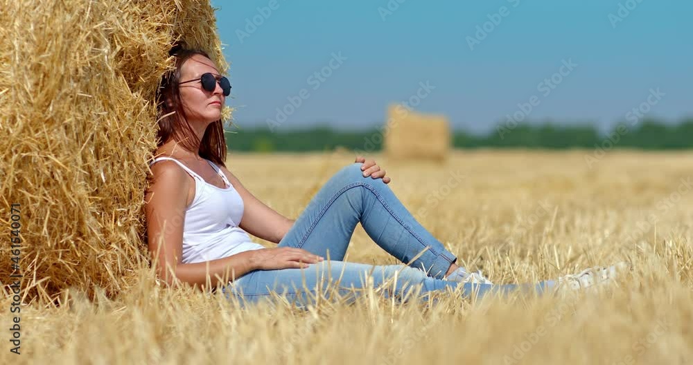 Portrait, a girl in sunglasses, resting by a golden haystack, resting in nature. Beautiful girl dreams of a mown wheat field, of a happy life. 4k, ProRes Portrait, a girl in sunglasses, resting by a golden haystack, resting in nature. Beautiful girl dreams of a mown wheat field, of a happy life. 4k, ProRes