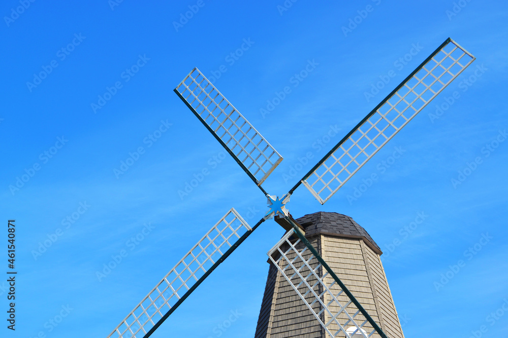 A wooden windmill under a bright blue sky
