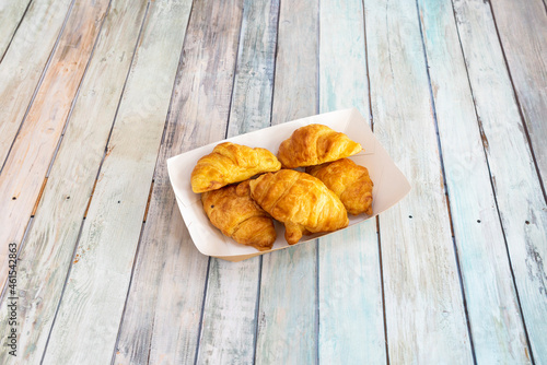 Small takeaway tray with butter croissants on wooden table