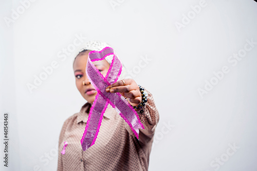 selective focus of african wowan, holding a ribbon covering portion of the face, close up image of a symbol- breast cancer awareness concept photo