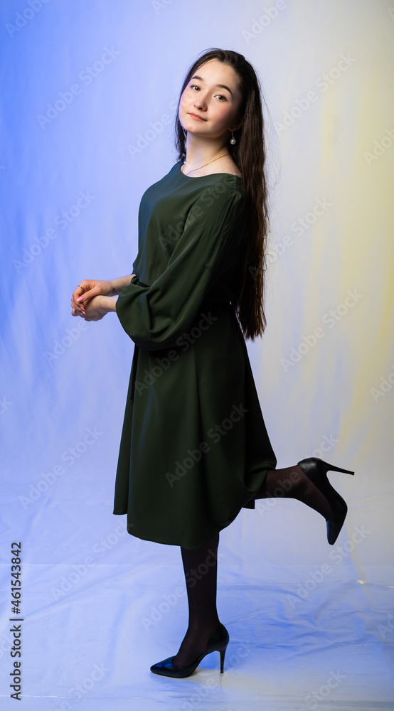 full-length portrait of a girl. model in a green dress, black shoes. long curly hair. colored background.