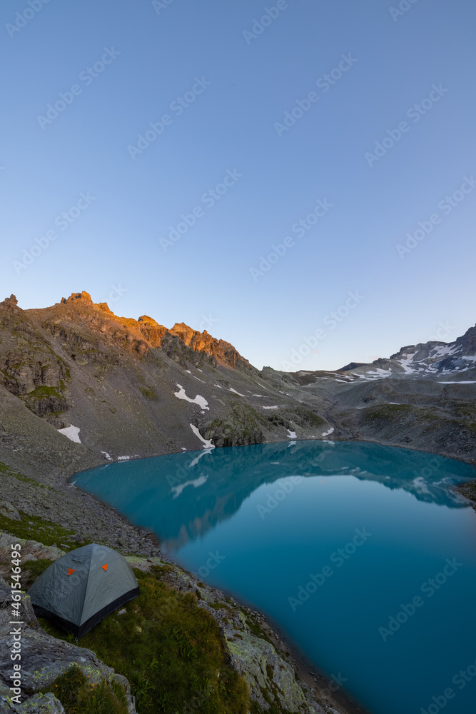 Wonderful scenery at an alpine lake called Wildsee in the canton of Saint Gallen. Epic sunset in the alps of Switzerland. Beautiful view with the tent in front and a perfect camping day.