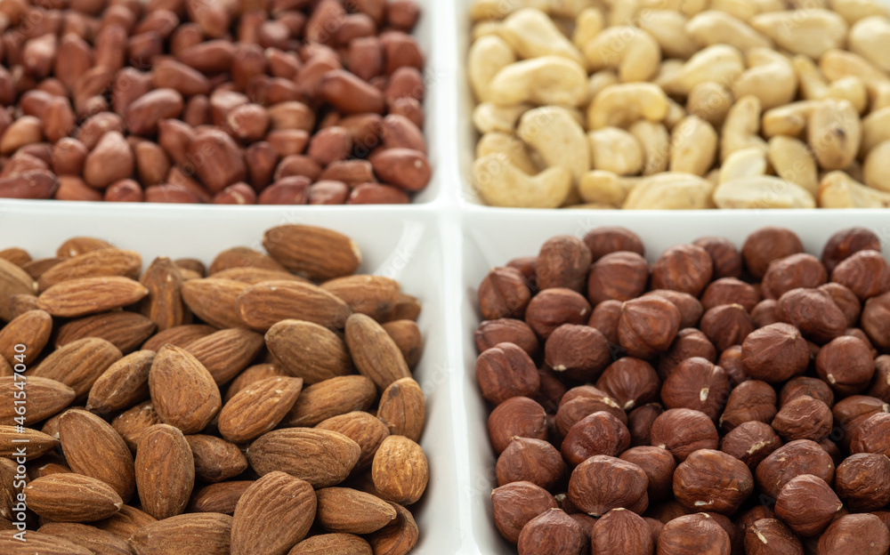 Four kinds of nuts in four compartments of combination plate: cashews, peanuts, hazelnuts, and almonds. Selective focus. Four kinds of nuts in four compartments of combination plate: cashews, peanuts, hazelnuts, and almonds. Selective focus.