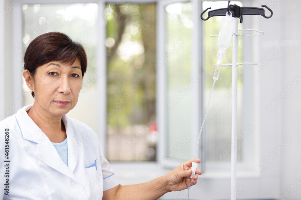 Portrait of a senior female nurse in middle asia Kazakhstan clinic intravenous drip hospital ward
