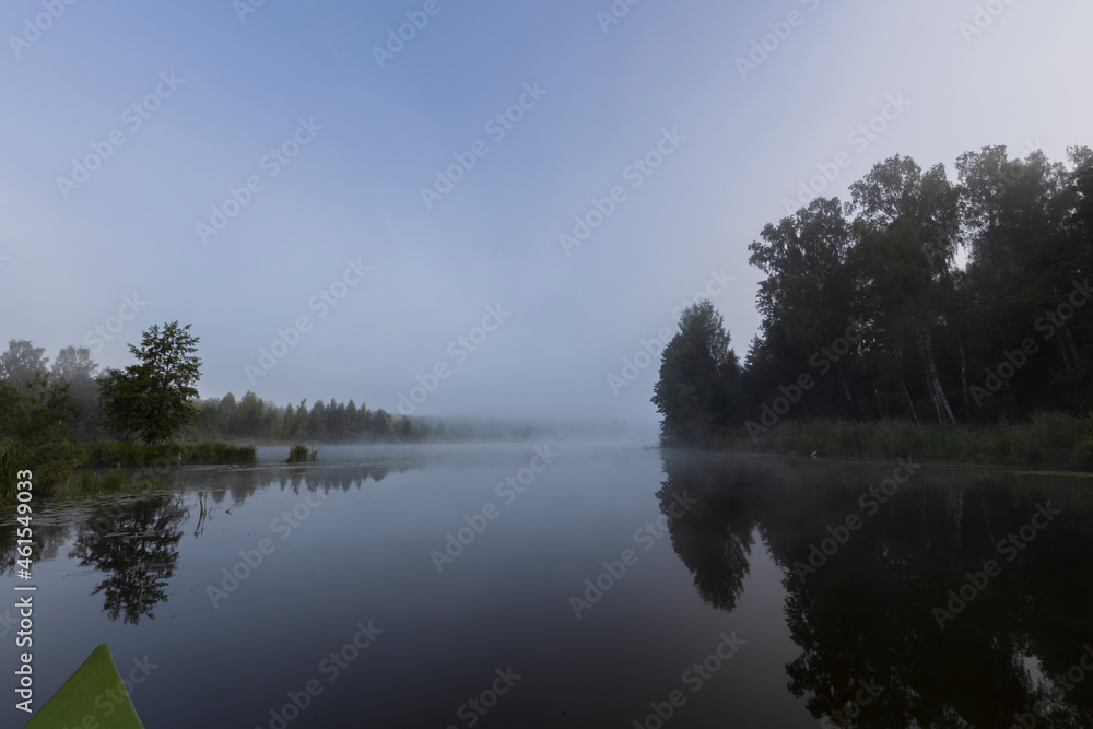 Mystical landscape at dawn. Early morning. Fog on the river. Beautiful dawn in the summer by the river. View from the boat to the morning landscape.