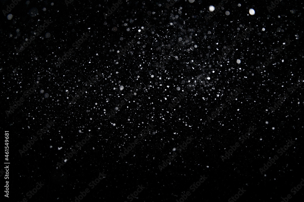Real falling medium sized snowflakes out of focus on black background for overlay blending mode on winter photography