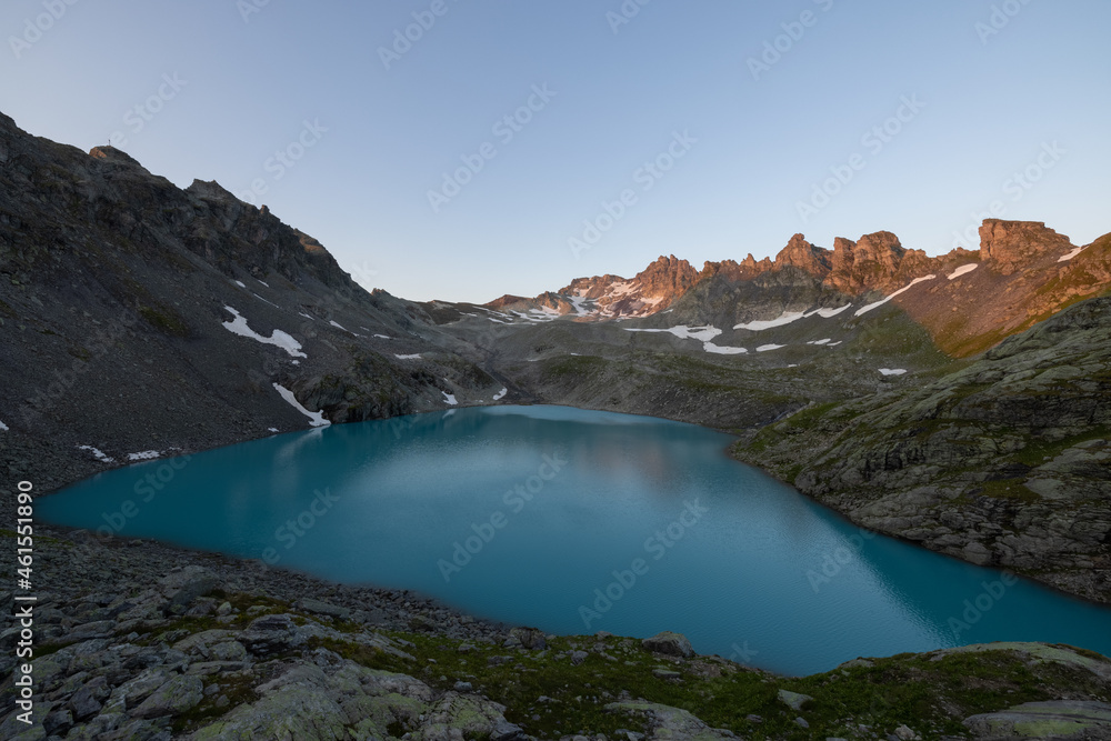 Wonderful morning view over an beautiful alpine lake called Wildsee in Switzerland. Amazing clear blue lake and the sun shine to the peaks of the glacier.
