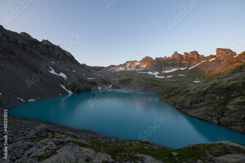 Wonderful morning view over an beautiful alpine lake called Wildsee in Switzerland. Amazing clear blue lake and the sun shine to the peaks of the glacier.