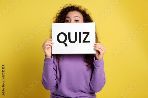 Photos African American woman holding sign with word QUIZ on yellow background