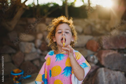 Young girl licking a  popsicle stick at the beach photo