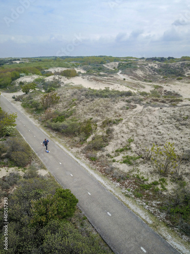 Drone shot of a man with long hair skating on a empty road photo