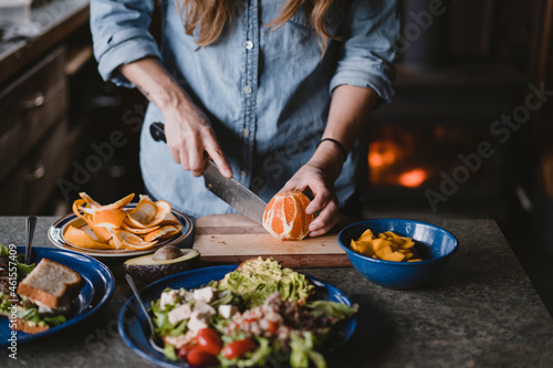 Woman slices orange for lunch on cutting board inside cabin