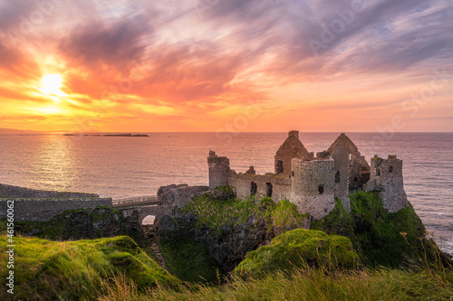 Sunset at ruins of Dunluce Castle located on the edge of cliff, Bushmills, Northern Ireland. Filming location of popular TV show Game of Thrones