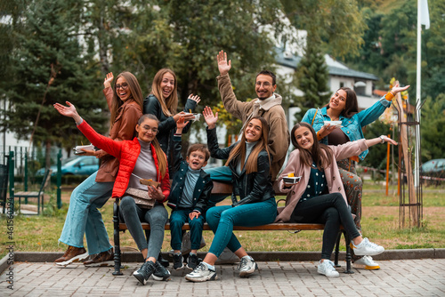 Portrait photo of a group of young people having fun while sitting in a park. Selective focus © Minet