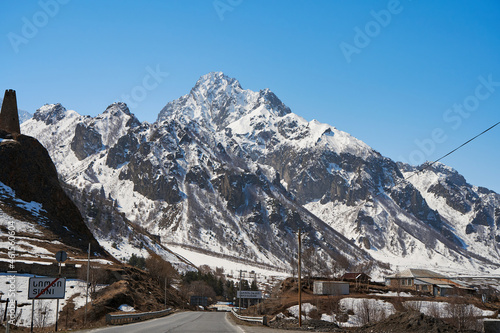 Early spring. The village is in the mountains. Snow caps on the tops of the mountains. Small village at the foot