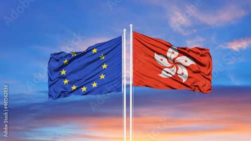 European Union and Hong Kong two flags on flagpoles and blue cloudy sky