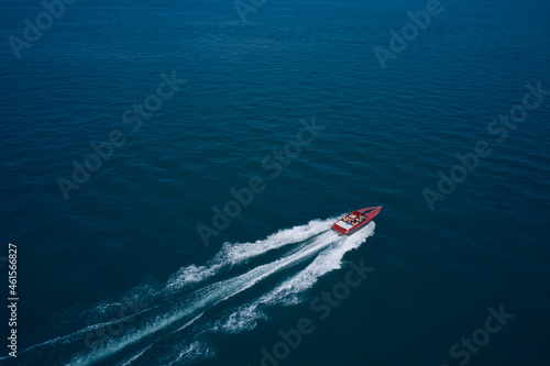 Red speed boat fast movement on the water top view. Diagonal boat movement on blue water top view. Travel - image. Top view of a red fast boat.