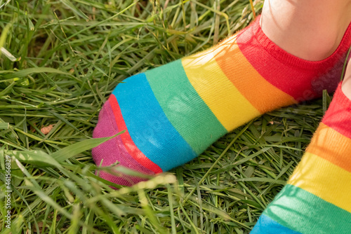 Rainbow socks on the girl's feet. Child's feet in colorful socks on the green grass.
