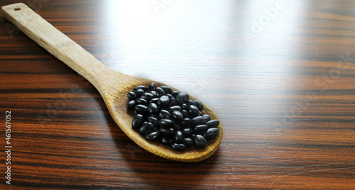 Beans spoon. Wooden spoon with black beans on the wooden rustic table. Brazilian food.