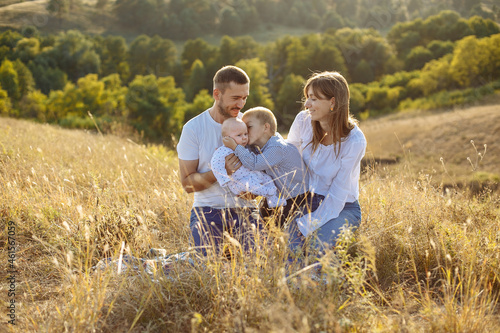 family with small children posing in nature on a background of tall grass and canvas