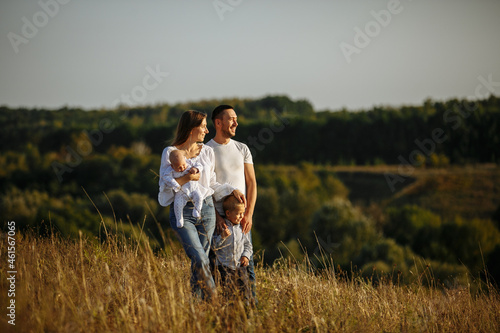 family with small children posing in nature on a background of tall grass and canvas