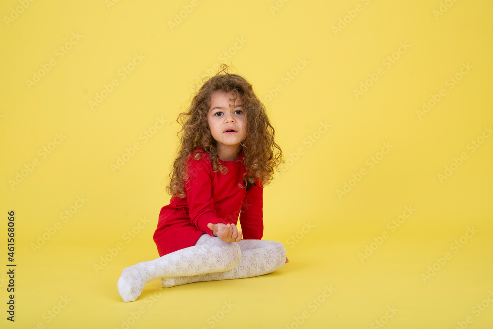 Portrait of a little curly girl on a yellow background Portrait of a little curly girl on a yellow background