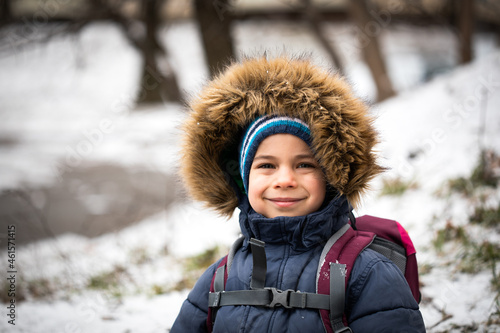 Portrait of smiling preschool boy in warm coat with hood in winter 