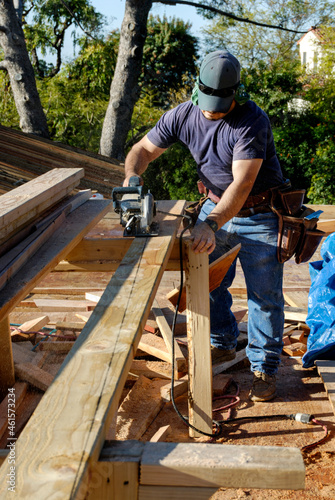 Carpenter using a power saw to cut lumber