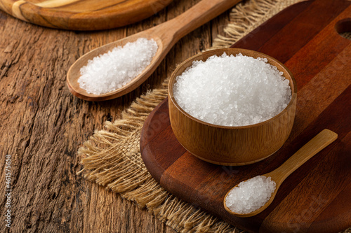 Coarse salt in bowl on wooden background.
